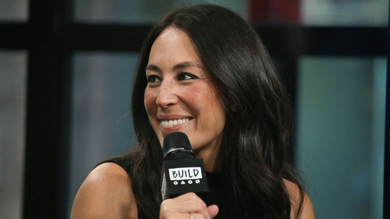 Joanna Gaines smiling with a microphone.
