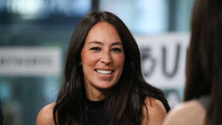 Joanna Gaines smiling in front of blurred background