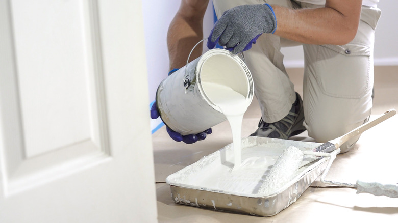 Kneeling person pouring white paint