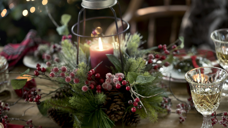 Holiday candle holder with pinecones and frosted cranberries centerpiece on table