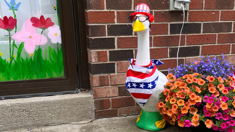 A porch goose wears glasses  and a red, white, and blue bandana with a matching hat