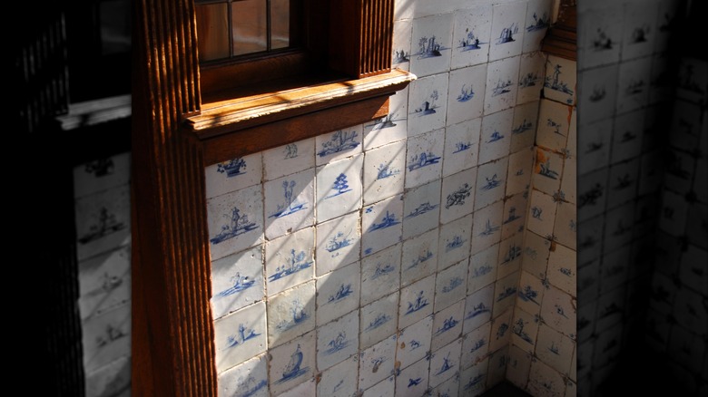 A wall featuring a Delft tile with wooden millwork.
