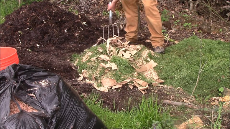 man tossing compost with pitchfork