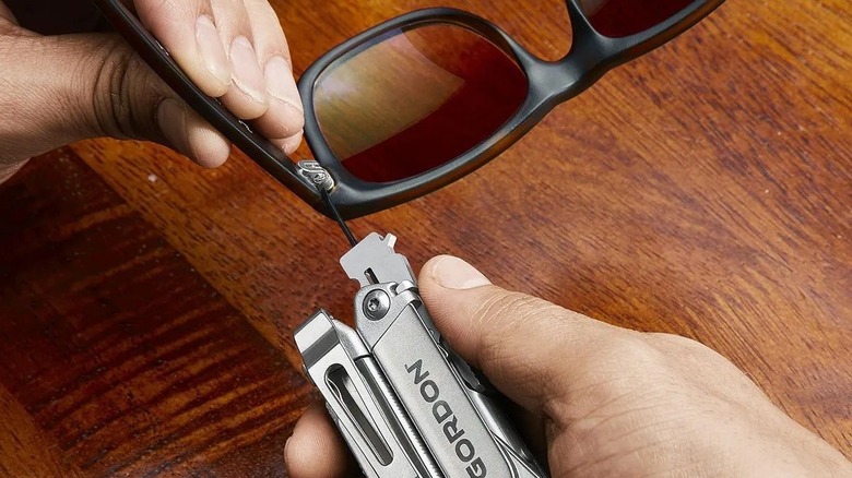 Person repairing glasses with a multi-tool
