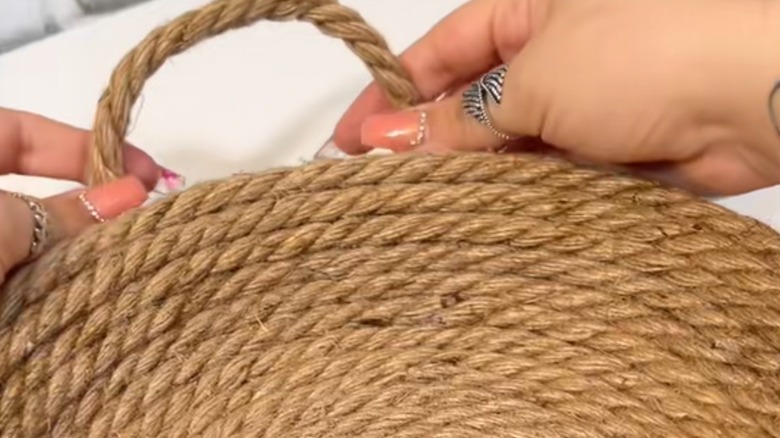 A pair of Caucasian hands coil jute rope onto a bowl.