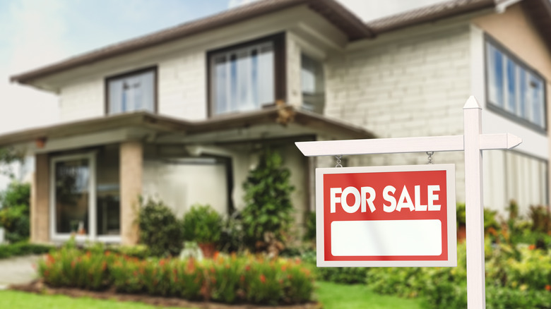 Modern house with a for sale sign in front of it