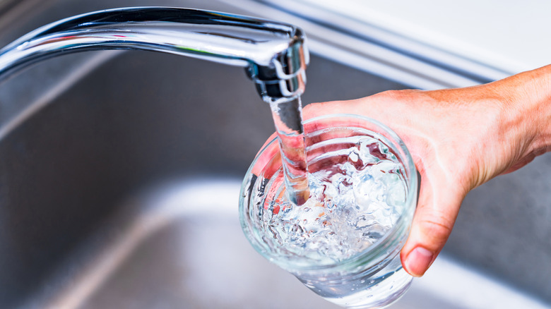 A woman fills a glass with tap water