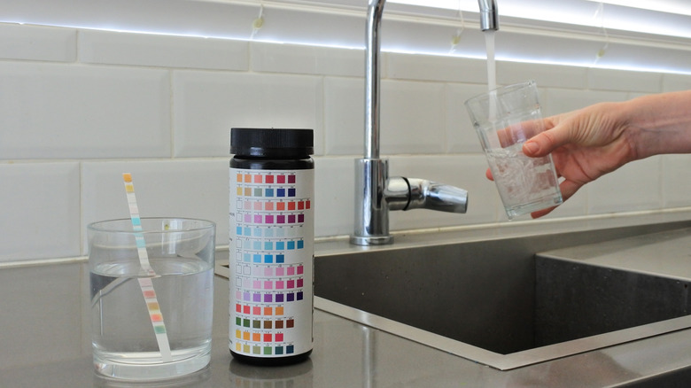A drinking water testing kit sits on a counter next to a faucet