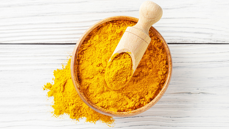 Turmeric powder in a bowl with a scoop on top of a table