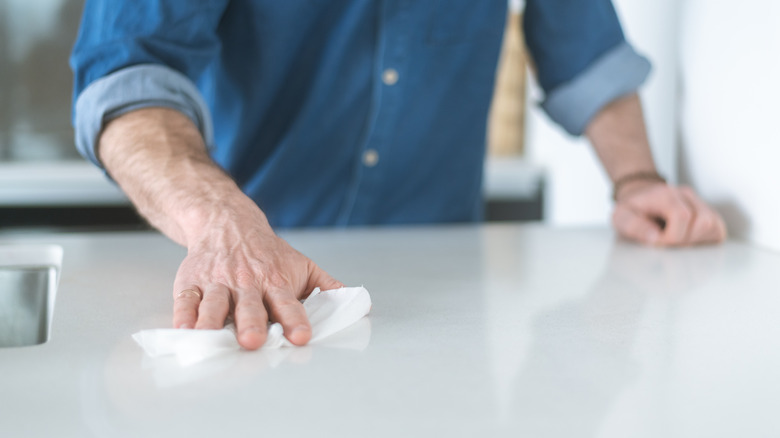 Man using a disinfectant on a kitchen counter