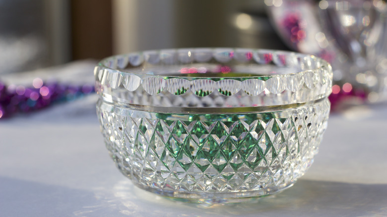 A crystal bowl with green beads inside
