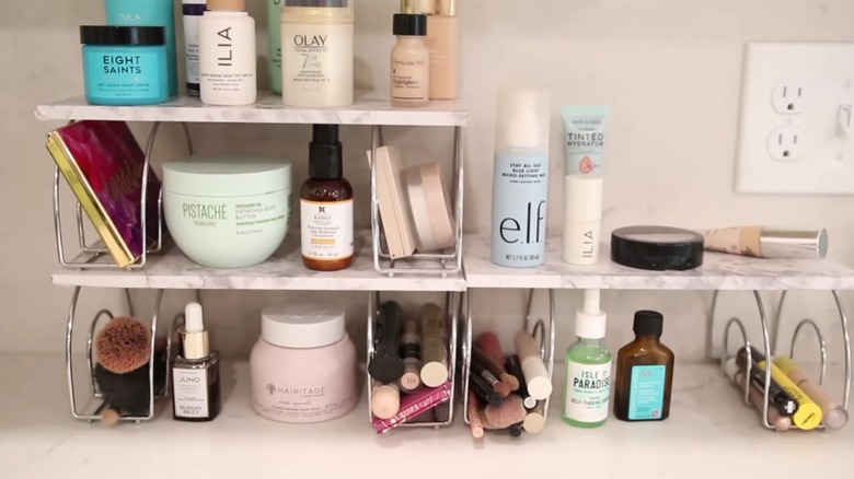 A DIY makeup stand in a bathroom made up of napkin holders and faux marble board.