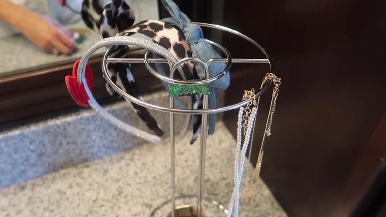 Two paper towel holders tied together to make a bathroom stand for hair accessories and jewelry.