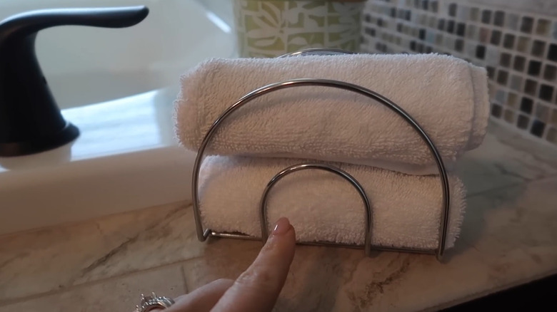 A napkin holder with rolled, white towels resting in it.