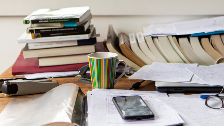 cluttered surface with books, glasses, and a mug