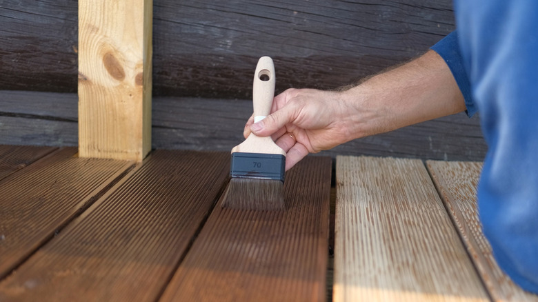 Hand holding brush and staining deck