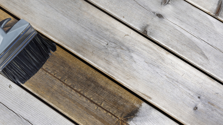 Brush applying natural oil to wooden deck boards