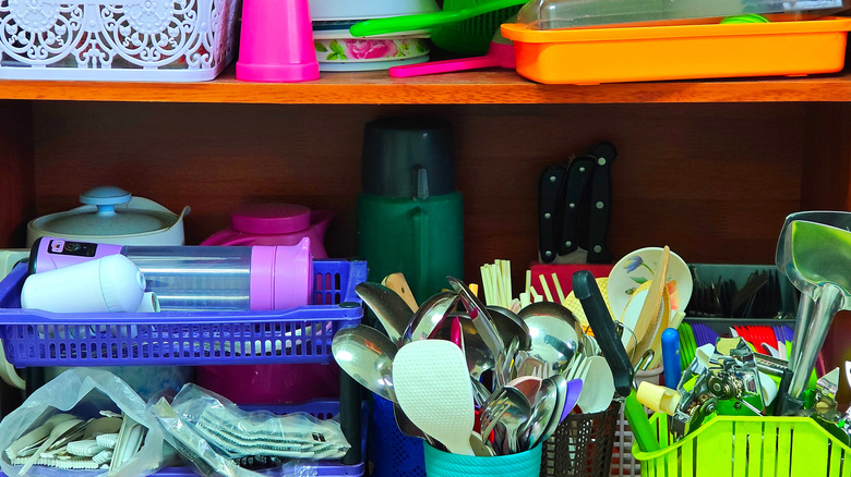 Shelves of unorganized clutter in kitchen cabinet
