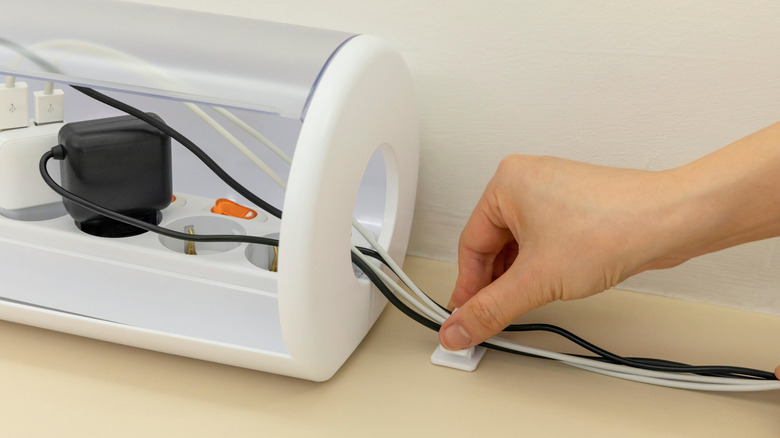 A handful of cables are being fed through a large hole at the end of aplastic cylinder