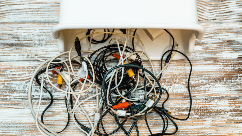 A set of black and white wires are tangled as they spill out of a white container.