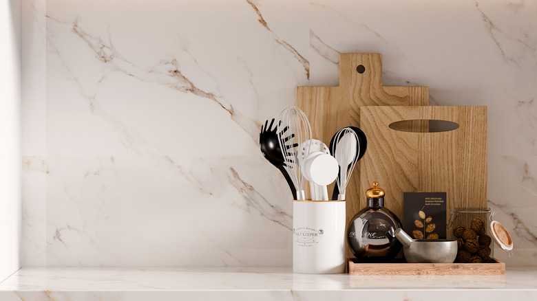 An organized kitchen countertop with utensil jar, cutting boards, and tea supplies