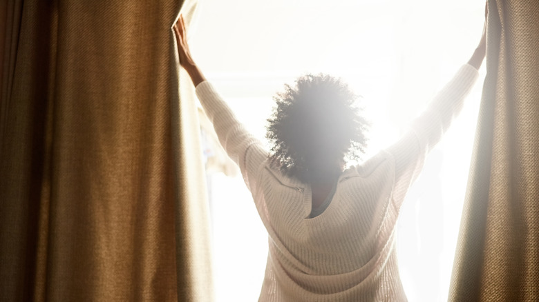 person opening curtains