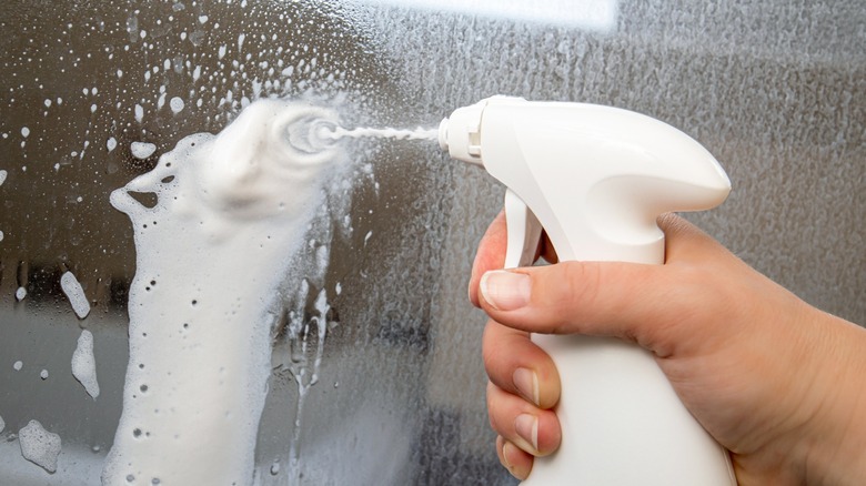 Spraying white substance on glass shower door