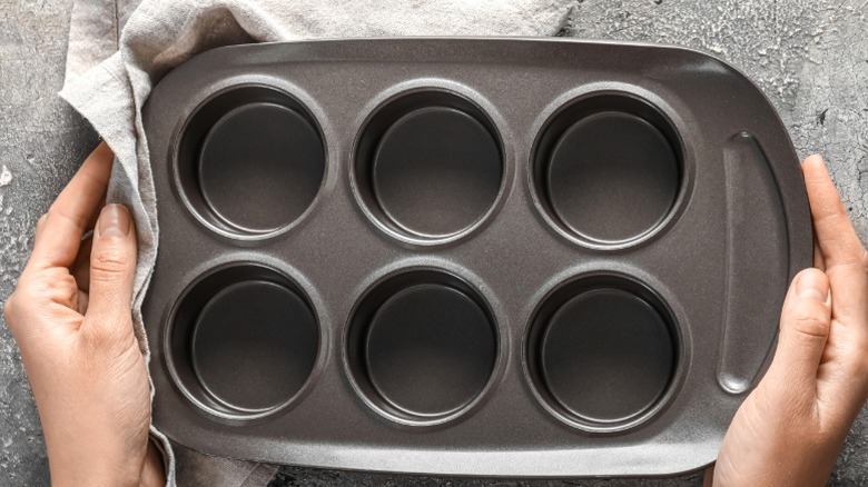 Person holding empty, clean jumbo muffin tin