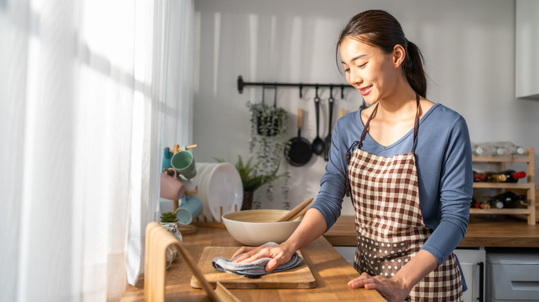 A woman tidies up a kitchen with an organized countertop