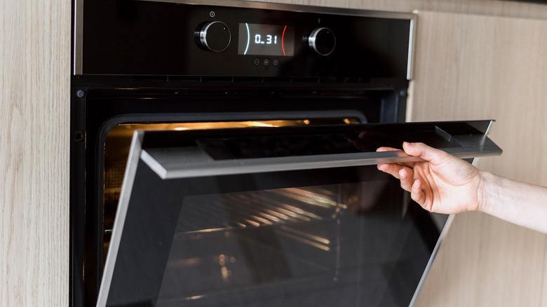 A person's hand pulling open an oven door