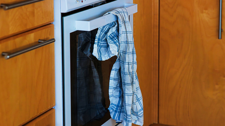 A blue and white towel hangs unevenly from an oven door handle
