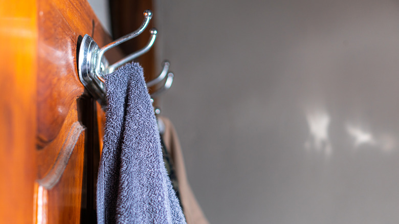 Close up of towels hanging off of a coat rack on a wooden background
