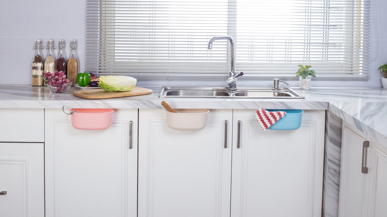 Open kitchen with three colorful storage bins hanging from the kitchen cabinets