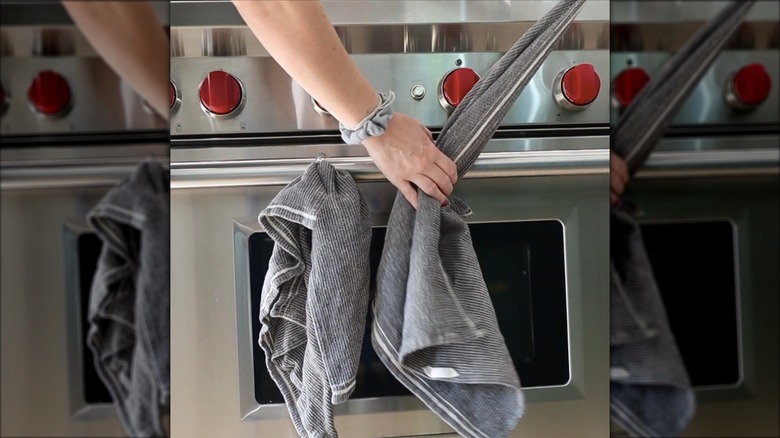 Screenshot of woman hanging kitchen towels via shower curtain rings on her oven
