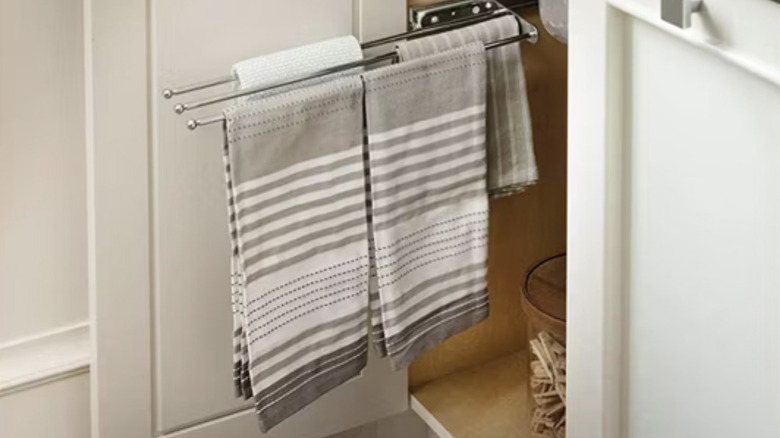 A towel bar with three rails holding brown and white striped towels.
