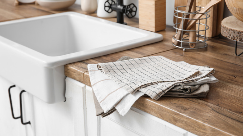 Kitchen towels folded up next to a sink.