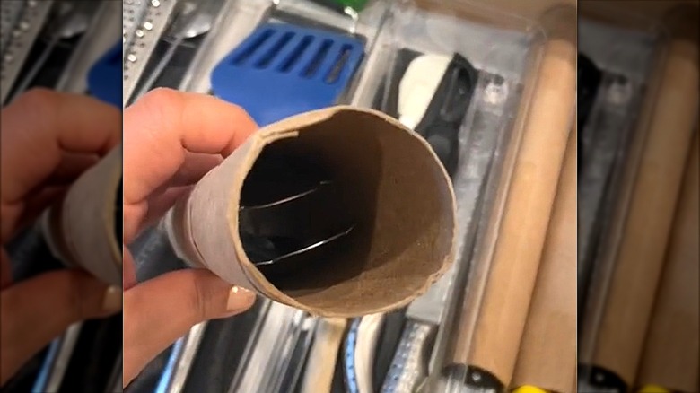Tongs inside of empty paper towel roll