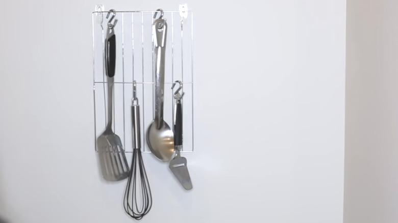 Kitchen utensils hanging on a wall-mounted Dollar Tree cooling rack