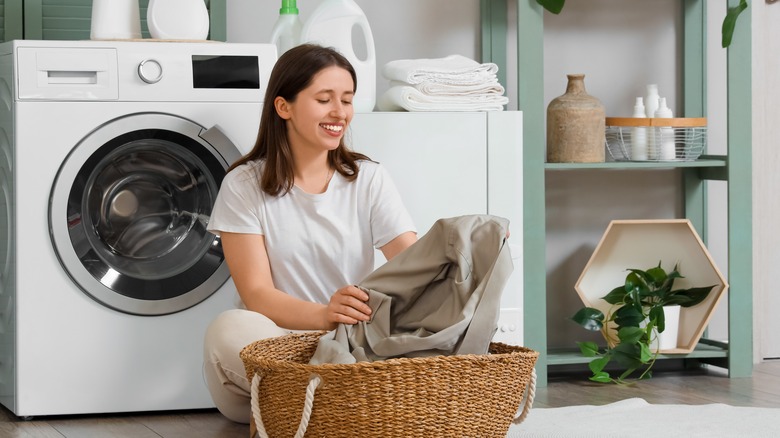 Woman sitting in laundry room taking laundry out of basket