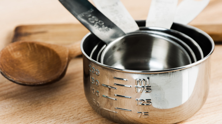 A set of metal measuring cups on a wooden table