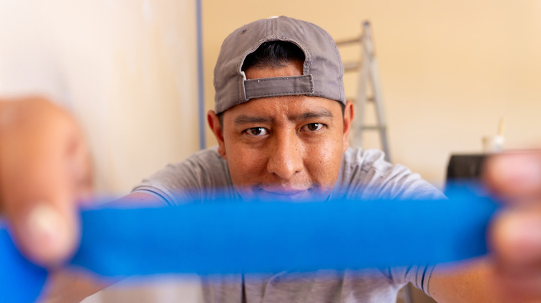 Man sticking painter's tape on camera lens.