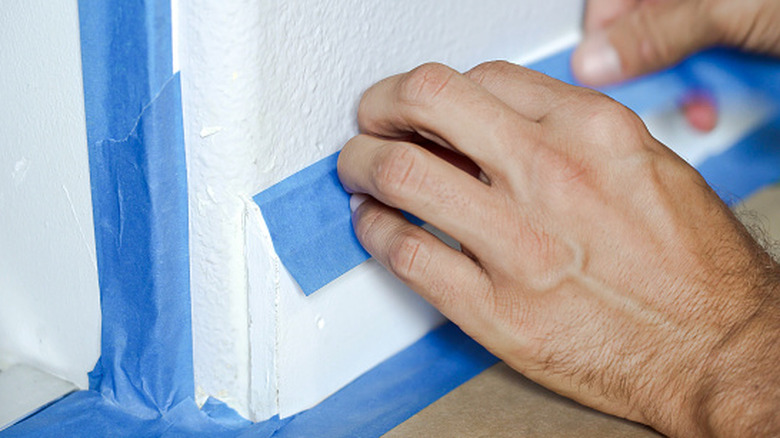 A man using painter's tap to protect molding.