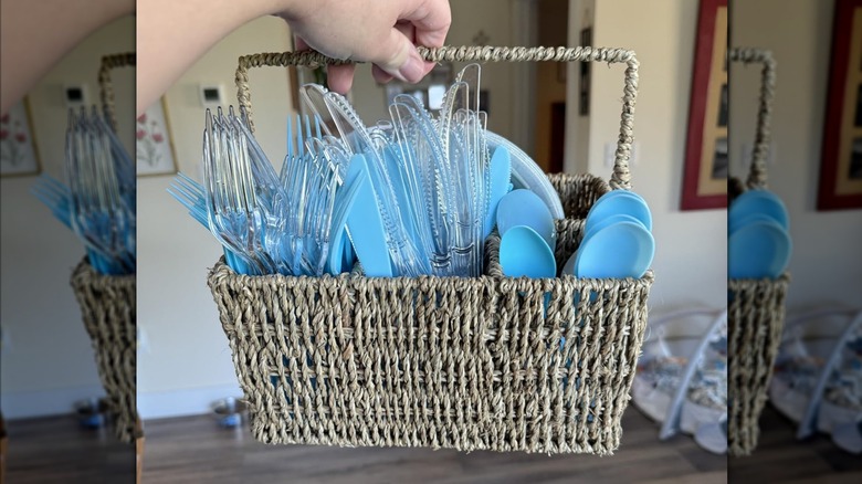 person holding the wicker basket filled with plastic forks spoons and knives