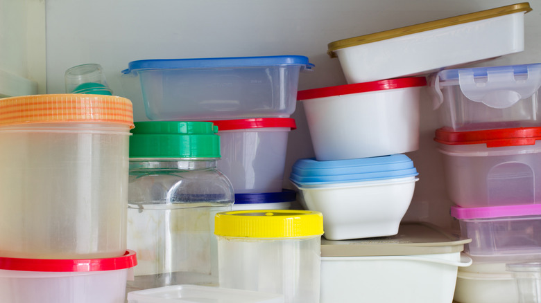 A messy stack of plastic food storage containers