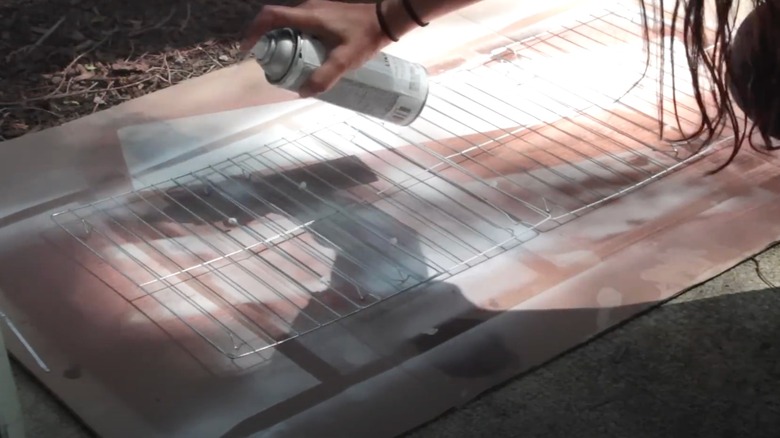 Woman spray painting her Dollar Tree cooling racks white.