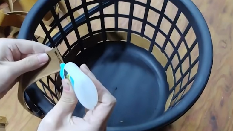 person gluing leathing strapping to laundry basket DIY