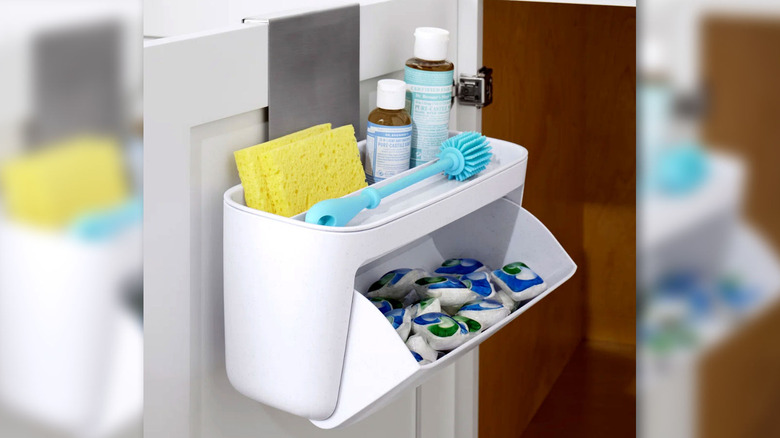 A storage basket hangs on the inside of the under-sink cabinet door to hold washing supplies