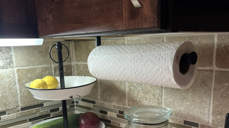 Paper towel roll hanging on mounted holder under cabinet.