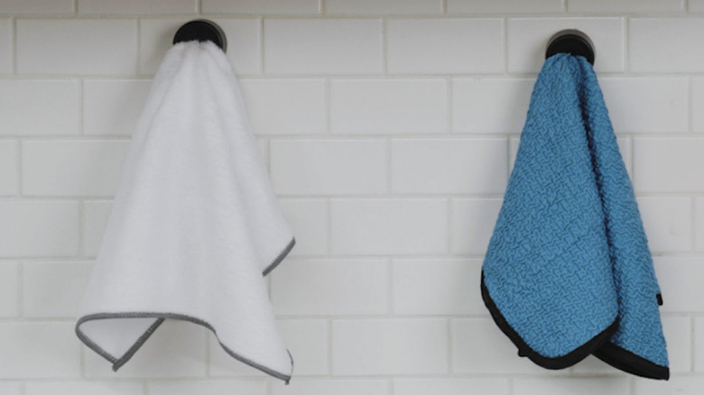 Dish rag hanging on towel hook attached to sink backsplash.