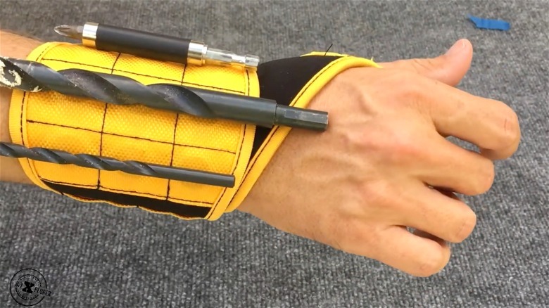 person's wrist with yellow BinyaTool magnetic wristband holding drill bits